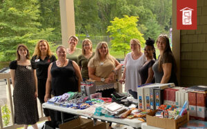 Image of staff standing by a table of school supplies at the 2023 Back to School event