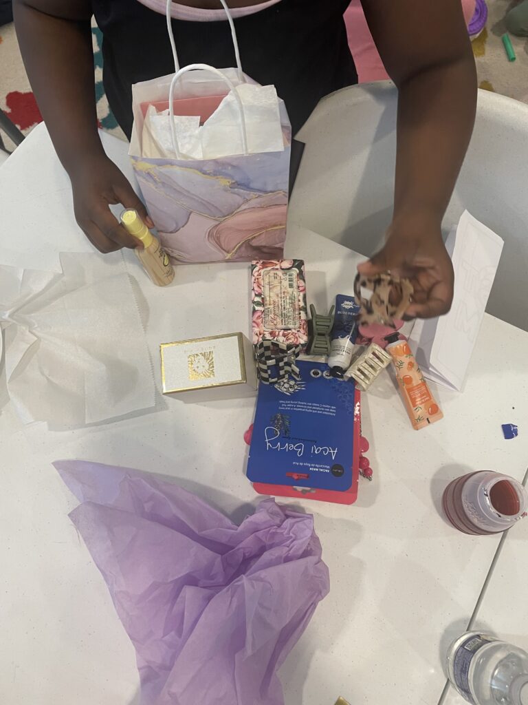 A child gathers an assortment of skin and hair care products to create a Mother's Day gift bag