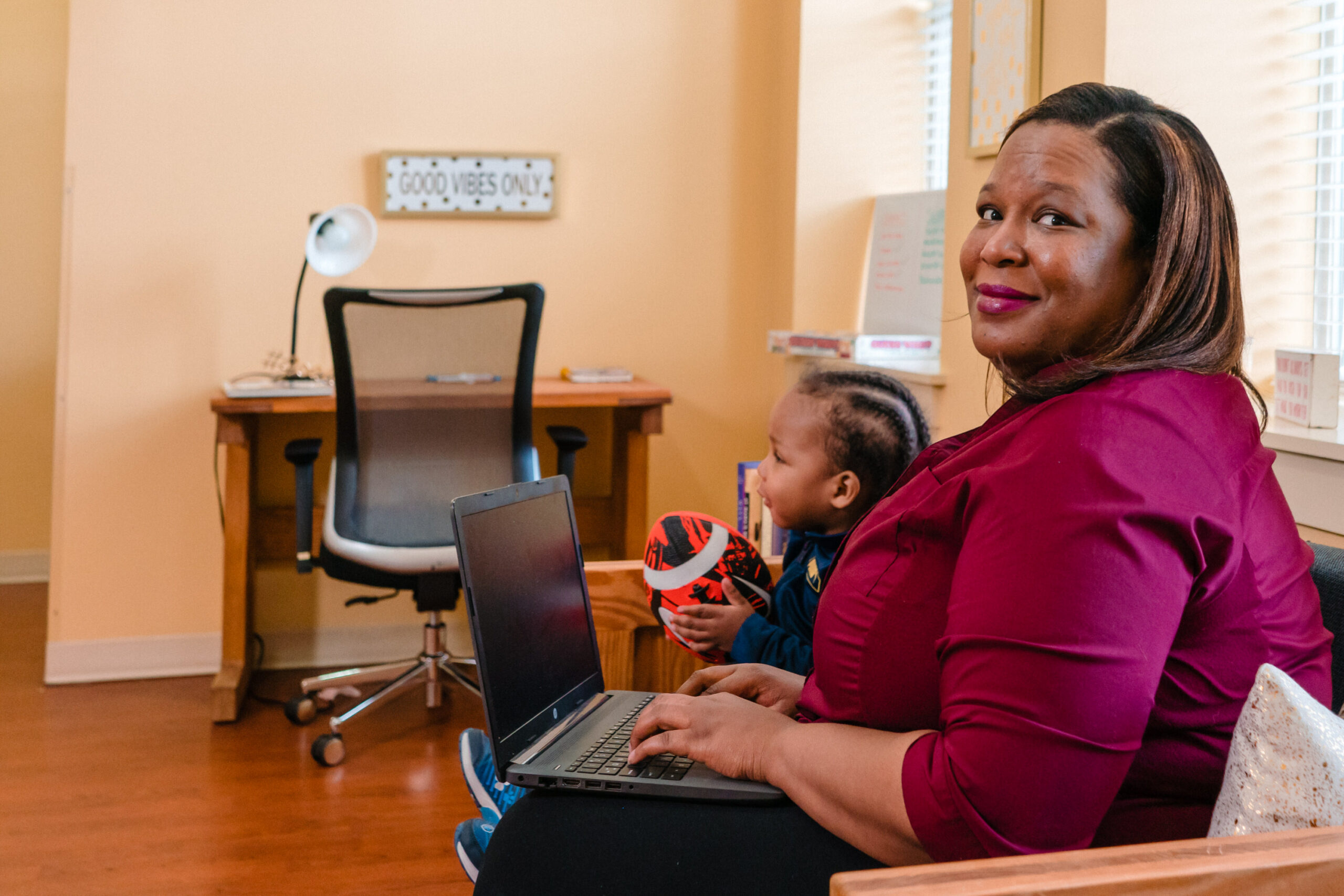 Mother working on a laptop while child sits nearby